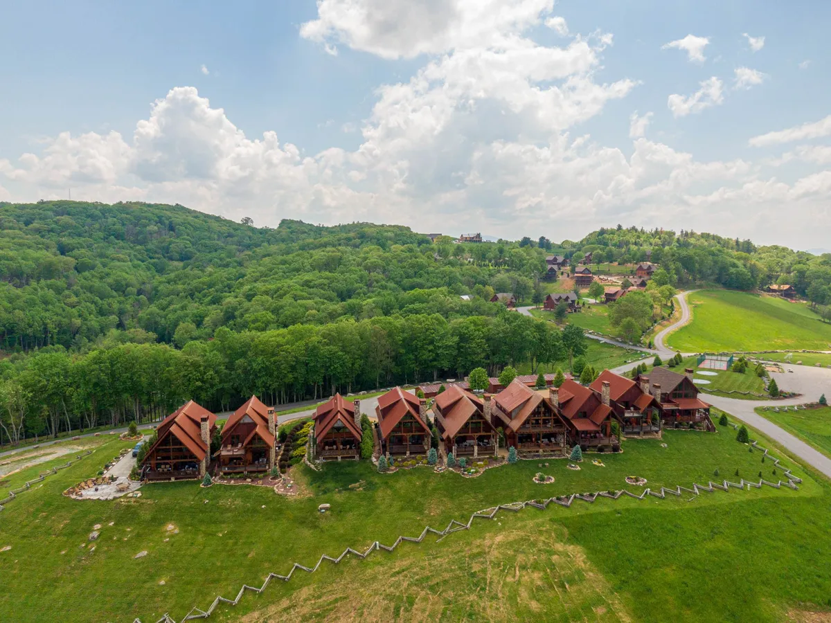 This image captures several lodge-style buildings nestled in lush greenery, with winding pathways connecting the structures. The inviting outdoor setting hints at room to roam, relax, and explore the area, all surrounded by tranquil natural beauty.