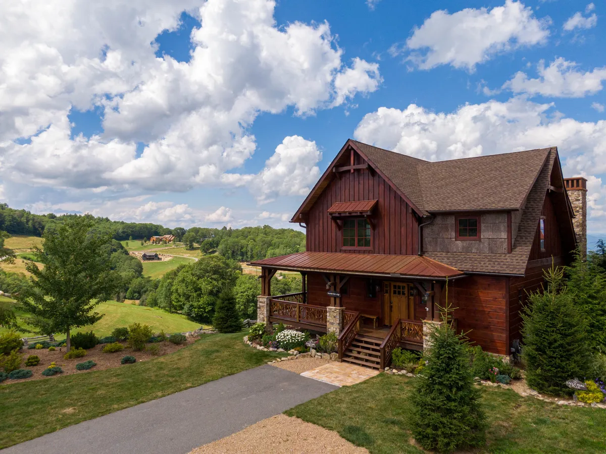 A rustic wooden house sits amid expansive green fields and a landscaped garden. The wide-open spaces and the homelike feel evoke the sense of freedom and possibility for outdoor activities, including pet-friendly adventures.