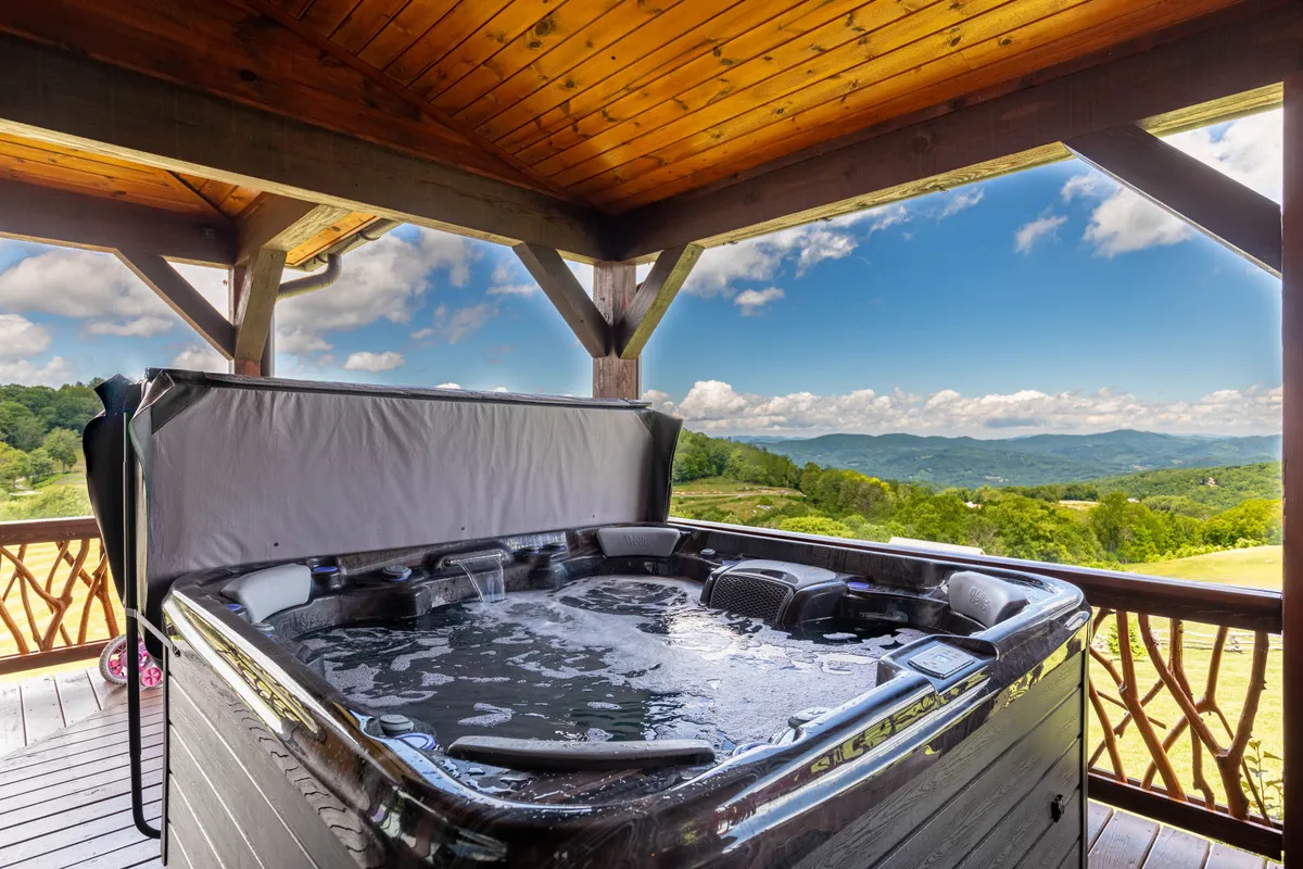 A tranquil outdoor hot tub sits on a wooden deck with expansive views of the surrounding mountains. This inviting scene captures the relaxation and togetherness families can enjoy after a day filled with adventure, all while taking in the natural beauty.